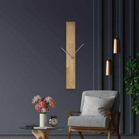 Modern falióra, fehér falra ragasztva, egyszerű fekete mutatókkal.